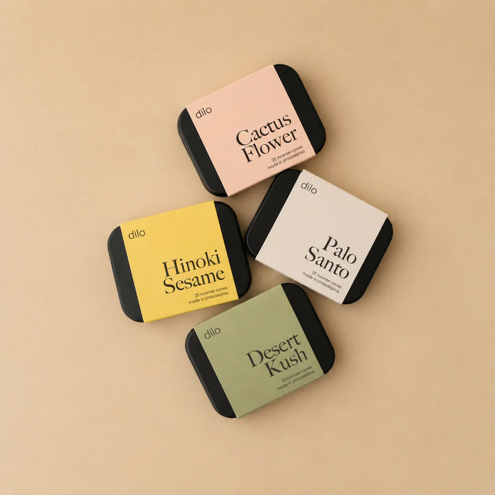 Four small rectangular dilo incense containers with different scents on a beige background