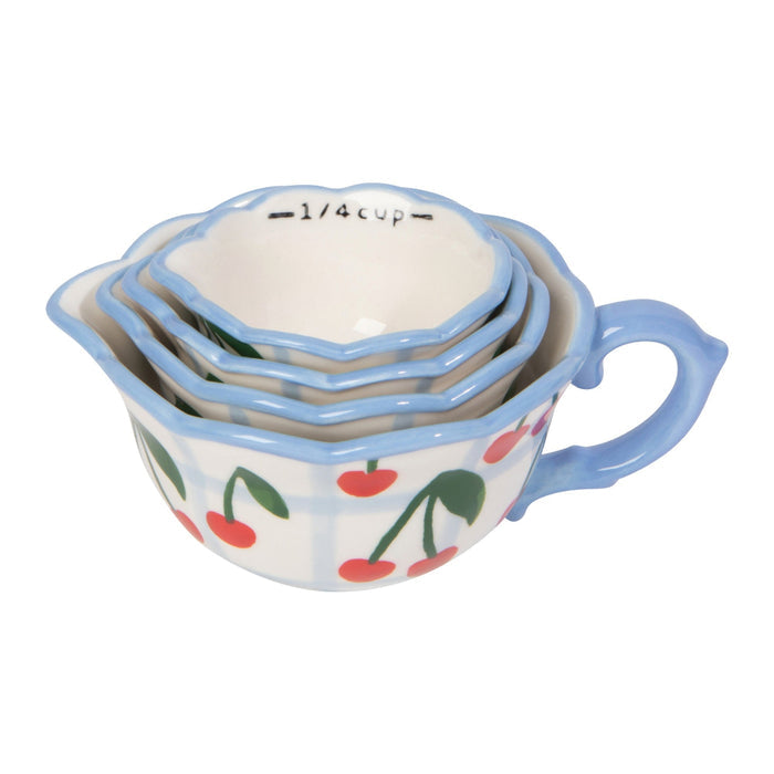 Set of four ceramic measuring cups with cherry design on a white background