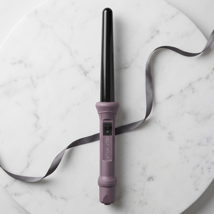 The Olla Bella 1" Ceramic Curling Iron in Plum Metallic with a gray ribbon displayed on a white marble background.