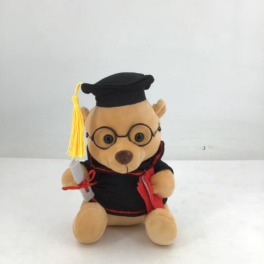 Plush toy bear in graduation attire with a cap, tassel, and gown on a white background