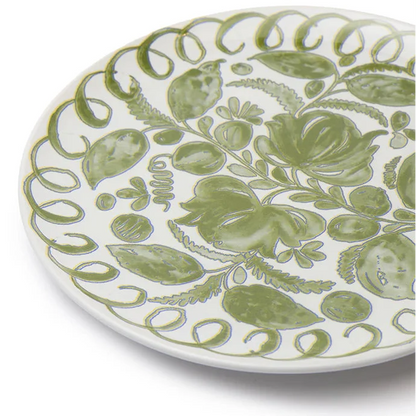 A close-up of a white ceramic plate decorated with a hand-painted green botanical pattern of leaves, flowers, and scrolling borders, set against a plain white background.