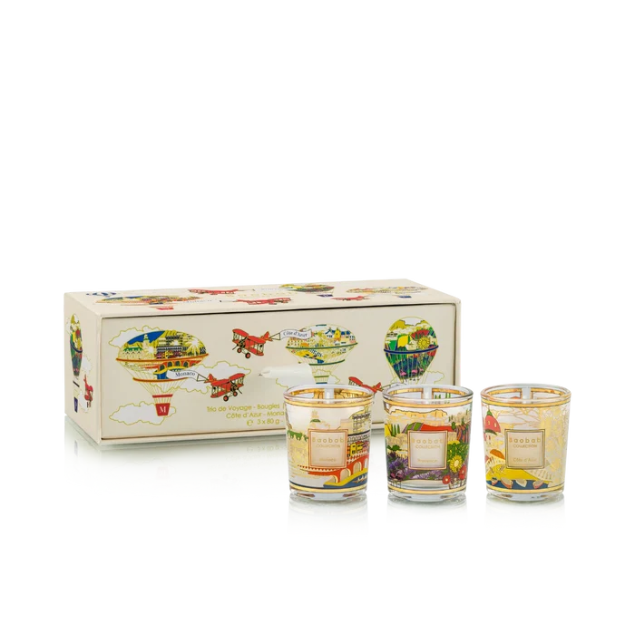 Set of three small candles with colorful designs in front of a decorative box on a white background