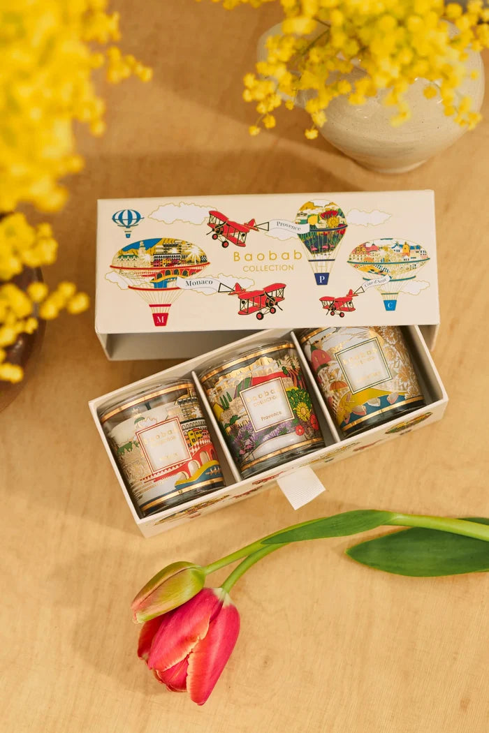 Set of small jars with decorative labels in a wooden box on a wooden surface with flowers in the background.