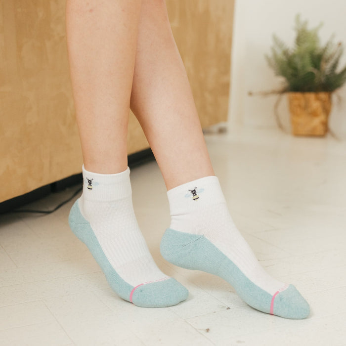 Quarter-length compression socks with a white and light blue design, featuring a bee graphic on the cuff.