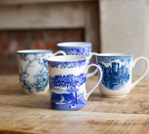 Four blue and white patterned mugs on a wooden surface with a rustic background.
