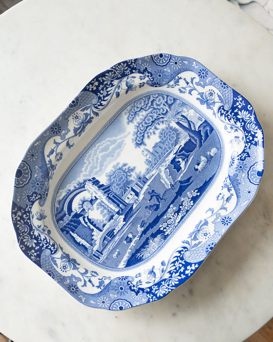 Vintage-style blue-and-white ceramic serving platter with floral and paisley patterns on the edges and a landscape in the center.