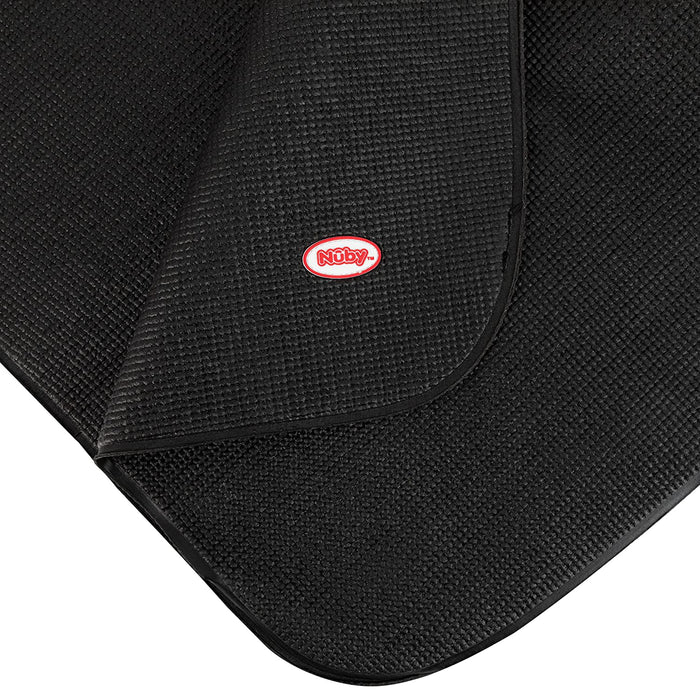 Close-up of a textured black Car Seat Undermat with curved corners, featuring a red and white Nûby logo stitched on top. One corner is lifted, revealing the anti-slip texture underneath.