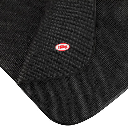 Close-up of a textured black Car Seat Undermat with curved corners, featuring a red and white Nûby logo stitched on top. One corner is lifted, revealing the anti-slip texture underneath.