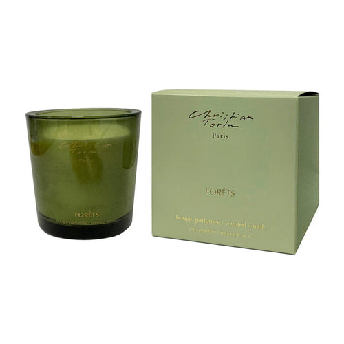 Green candle with packaging featuring 'Christian Tortu' branding on a white background