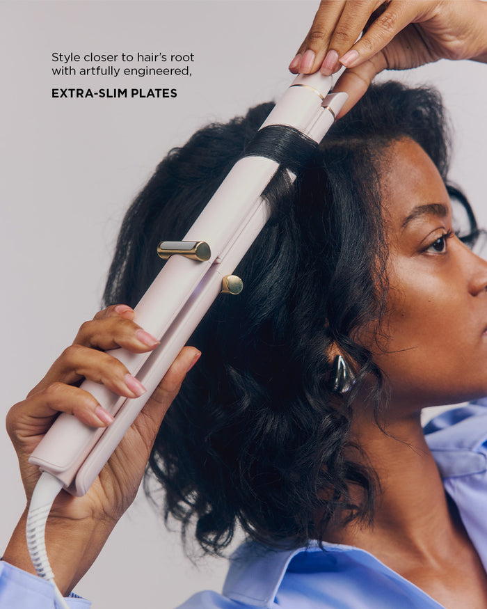 Person using a hair straightener on their hair with text highlighting 'Extra-slim plates'.