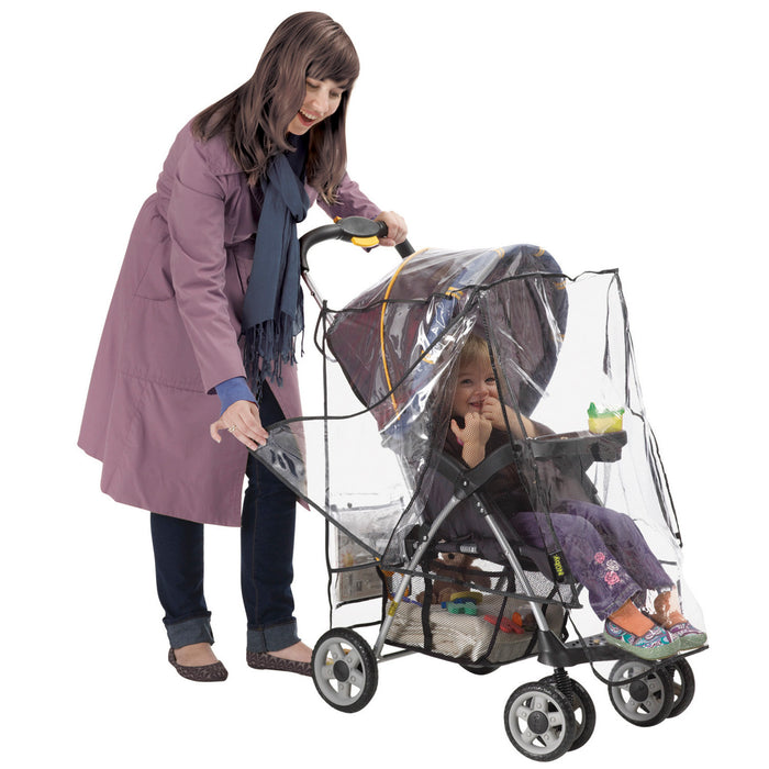 A woman in a purple coat pushes a stroller with the Deluxe Stroller Weather Shield. Inside, a smiling child holds a green sippy cup. The stroller features handy under-seat storage.