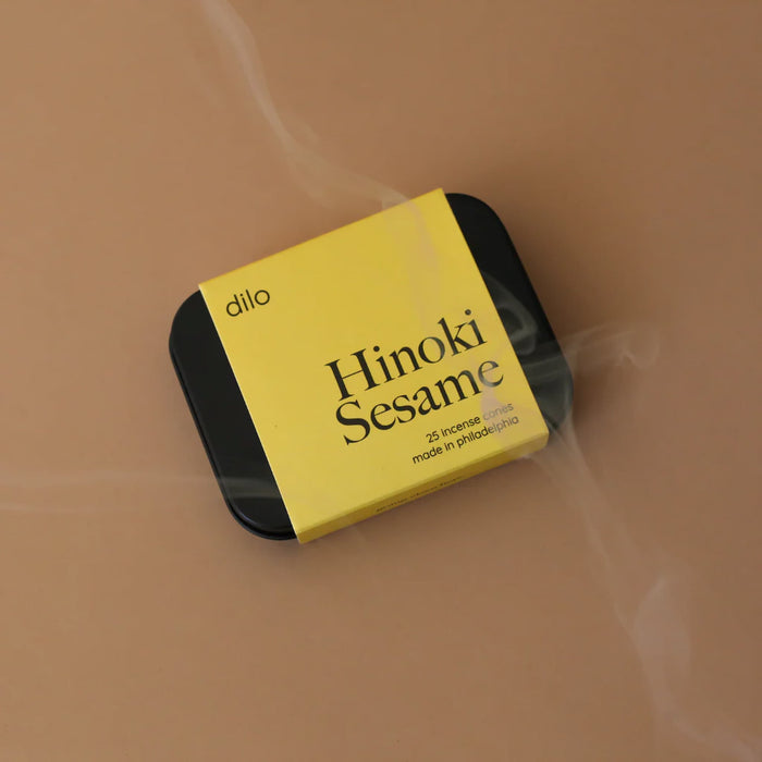 Yellow and black packaging of 'Hinoki Sesame' incense sticks by 'dilo' on a beige background.