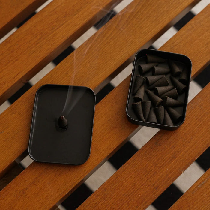 Black incense burner and container on a wooden surface