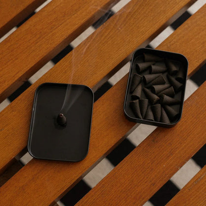 Black incense burner and container on a wooden surface