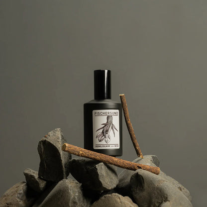 Black bottle of Fischersund 23 room spray with label on a rock against a gray background