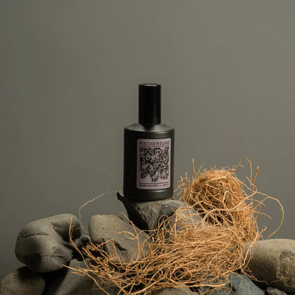Bottle of Fischersund 54 room spray on a stone surface with hay, against a gray background