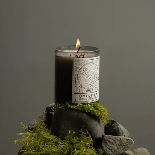 Fischersund Utilykt candle with a label on a stone and moss structure against a gray background