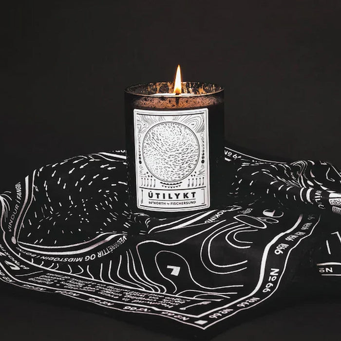 Fischersund Utilykt candle with a label on a black and white patterned cloth against a dark background