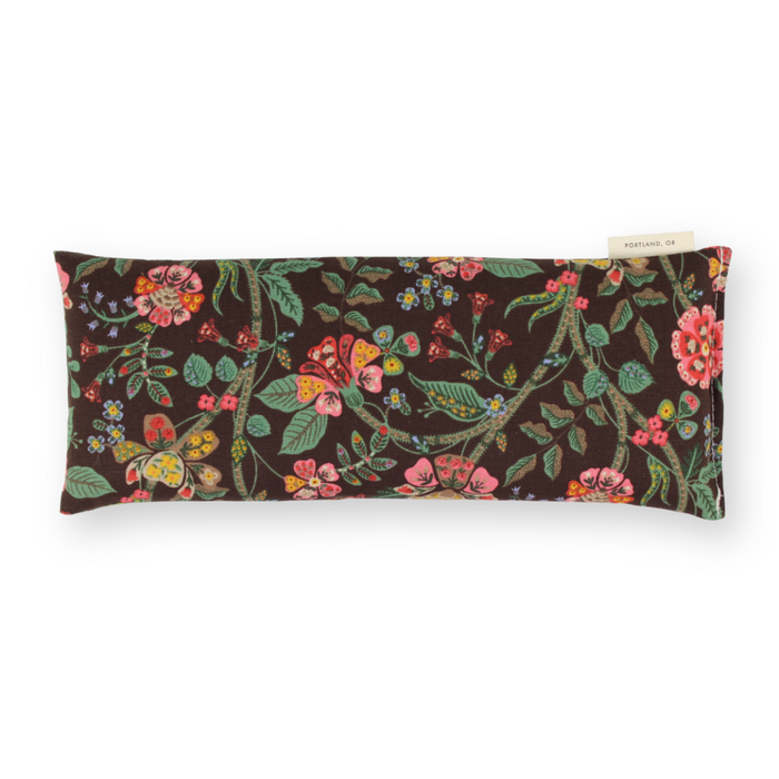 Brown background with floral print eye pillow on a white background.