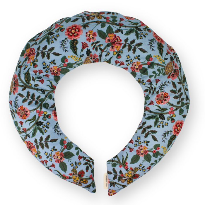A floral printed neck wrap with a blue background and flowers in orange, red and pink, featuring a removable cotton cover.