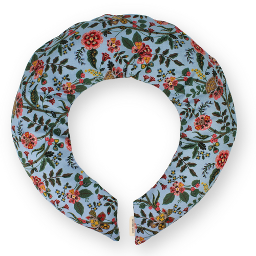 A floral printed neck wrap with a blue background and flowers in orange, red and pink, featuring a removable cotton cover.