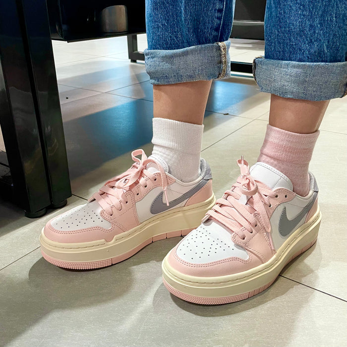 Quarter compression socks in white and pink worn with pink and gray sneakers, legs crossed on a tiled floor.