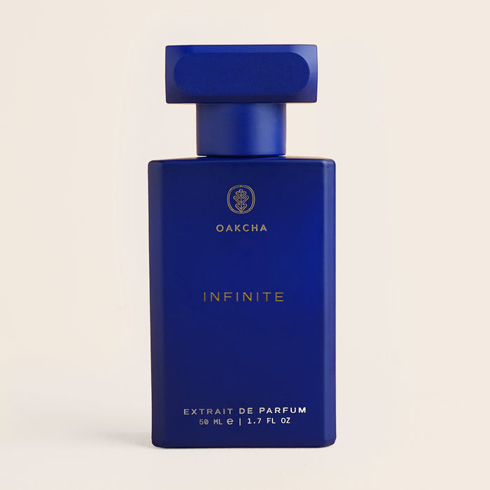 Front view of Infinite men’s perfume bottle showing deep cobalt-blue rectangular bottle and cap on a light beige background
