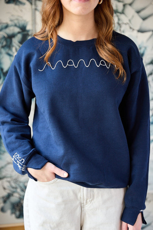 A navy sweatshirt with a white hand-embroidered 'maman' logo on the front.