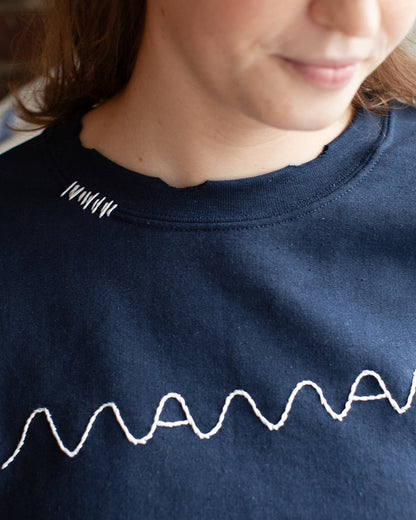 A navy sweatshirt with a white hand-embroidered 'maman' logo on the front.