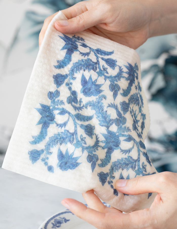Person holding a reusable dishcloths with blue-and-white floral patterns.