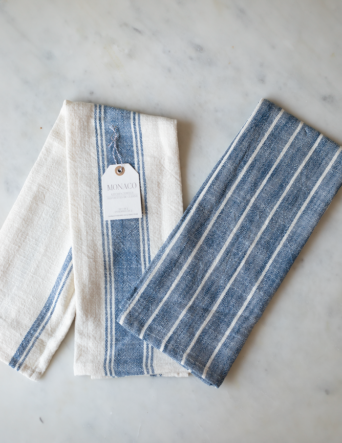 Two folded striped cotton kitchen towels, one with with a blue stripe and the other blue with a white strips.