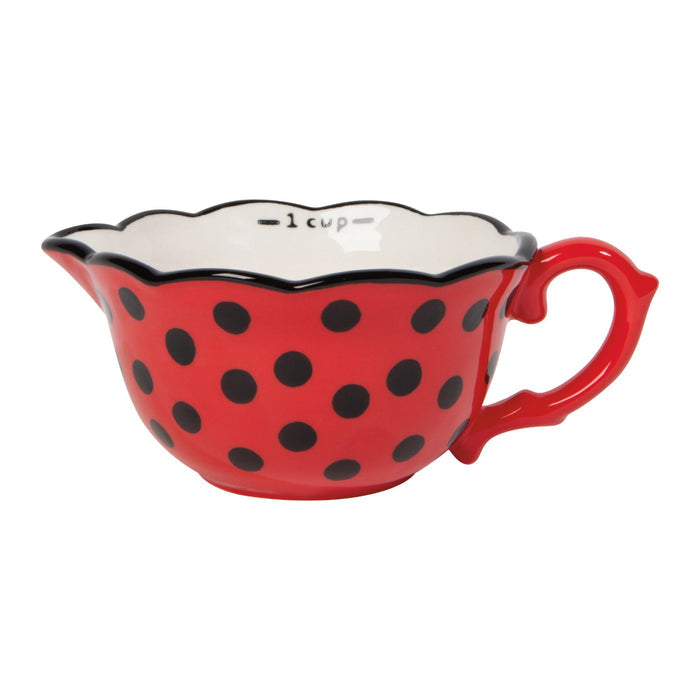 Red measuring cup with black polka dots on a white background