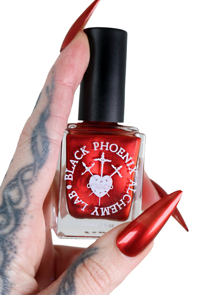 Nail polish bottle with a black cap and visible brand name held by a hand with brown nail polish.