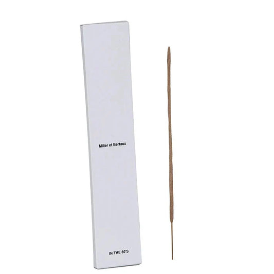 A single incense stick standing vertically next to its tall white rectangular box, which has the text 'Miller et Bertaux' and 'IN THE 80'S' printed on it, set against a white background.