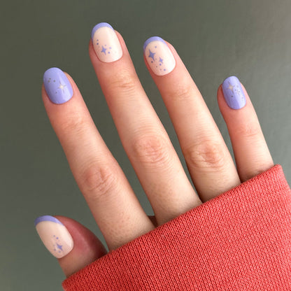 Mixed Purple Sparkle | Extra Short | Round - Tab Press-On nails with violet tips and star designs on natural base in soft light