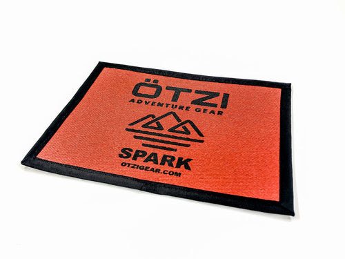 Rectangular red fabric patch with Ötzi Adventure Gear Spark logo and mountain design.