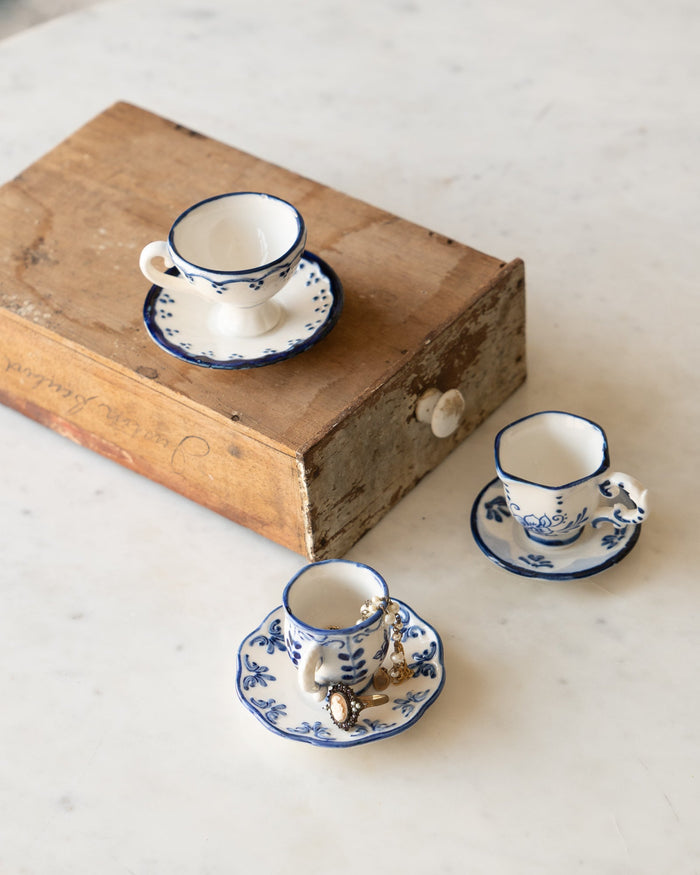 set of tiny tea cup and saucers with blue and white floral details.