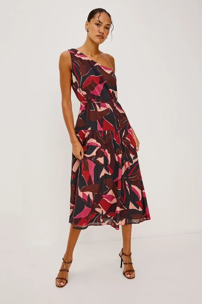 Woman wearing a one-shoulder dress with abstract pattern on a white background
