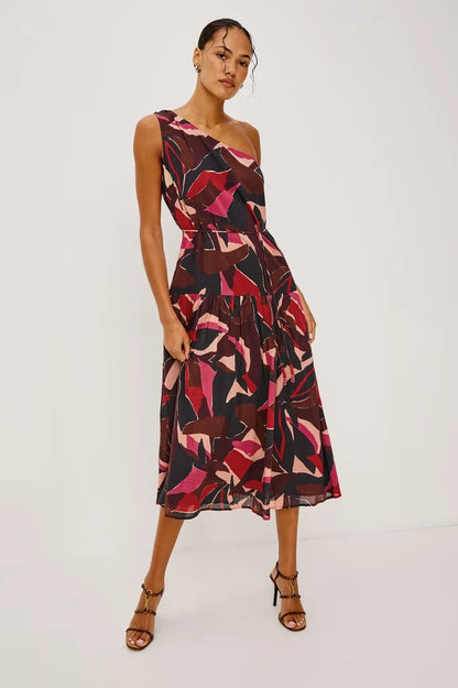 Woman wearing a one-shoulder dress with abstract pattern on a white background