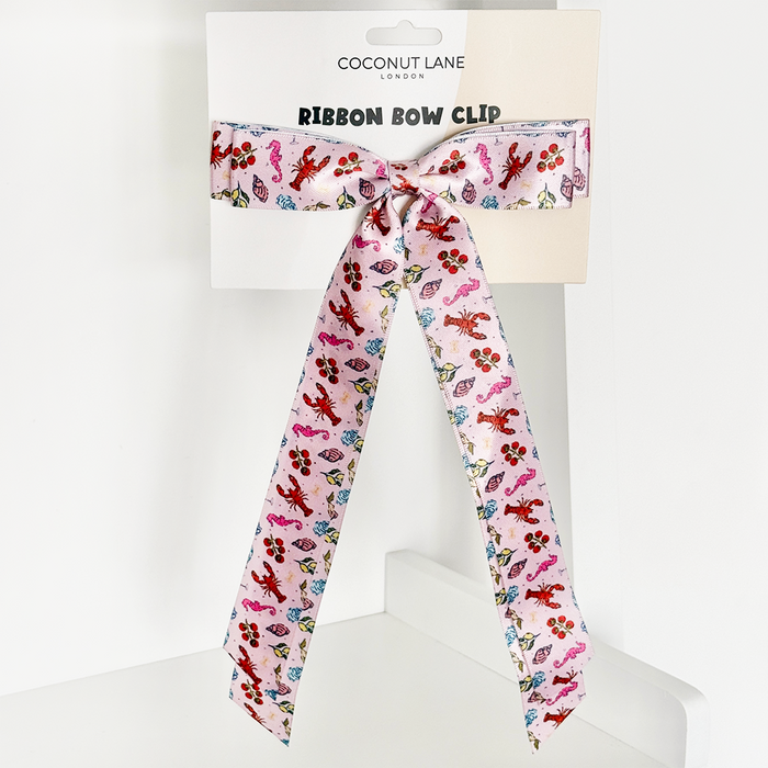 Pink ribbon bow clip with colorful animal print, displayed on a Coconut Lane branded card.