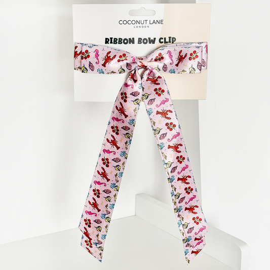 Pink ribbon bow clip with colorful animal print, displayed on a Coconut Lane branded card.