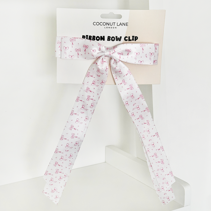 Pink flamingo-patterned ribbon bow clip by Coconut Lane on a white shelf.