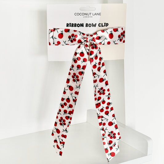 Red ribbon bow clip with cherry pattern, presented in Coconut Lane branded packaging.
