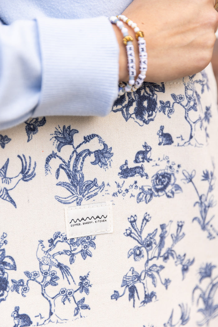 Person holding a tote bag with a blue-and-white floral toile pattern and the maman logo.