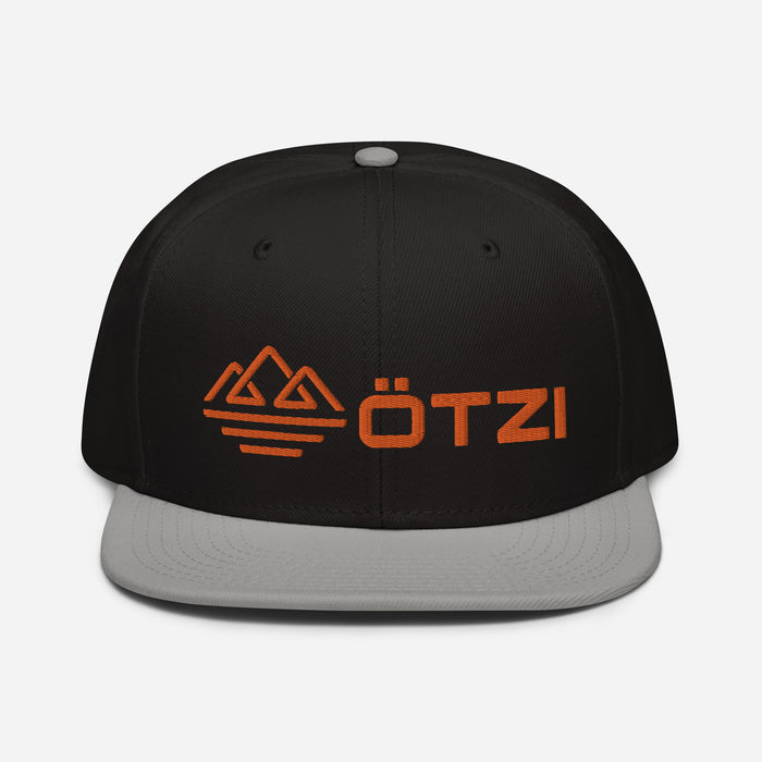 Black snapback hat with gray brim and orange ÖTZI logo on the front