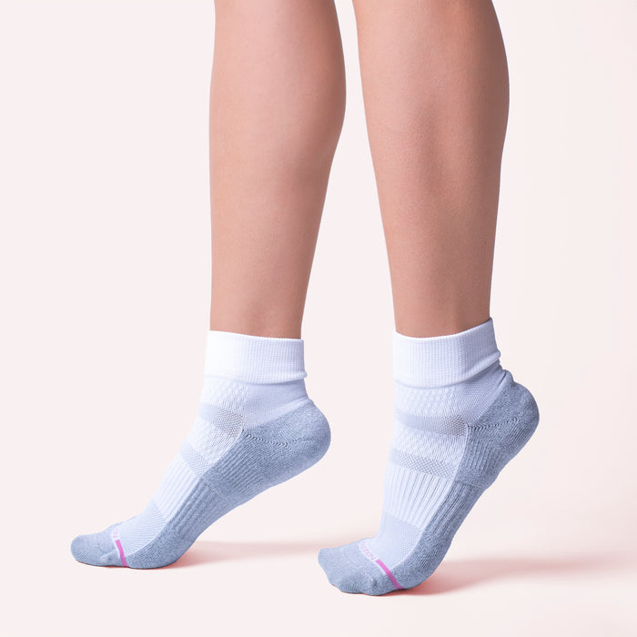 Quarter-length compression socks in white and gray with a pink accent, shown on a model's feet.