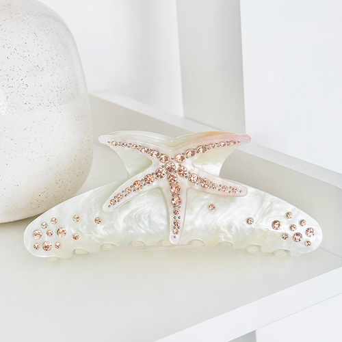 Pearl white starfish-shaped hair claw with pink rhinestones, displayed on a white surface.