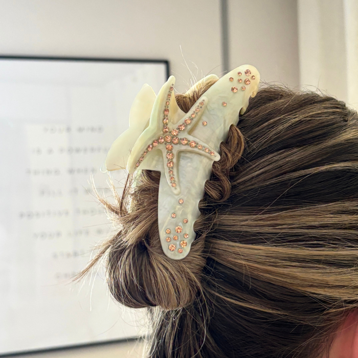 Woman’s hair pinned up with a gold starfish-shaped claw clip featuring a bold, glossy tropical design.