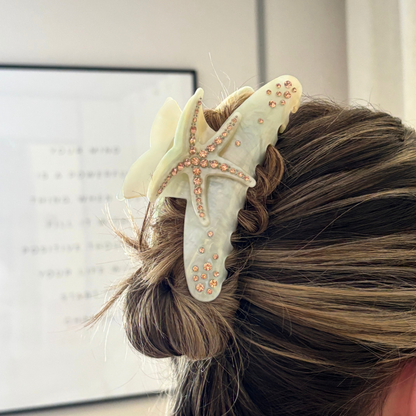 Woman’s hair pinned up with a gold starfish-shaped claw clip featuring a bold, glossy tropical design.