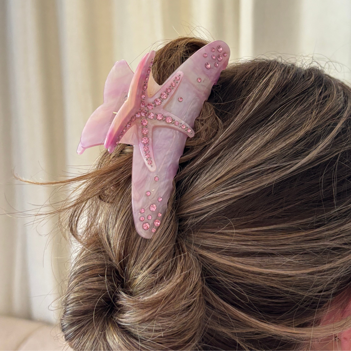 Pink starfish-shaped Coconut Lane claw clip holding a bun.